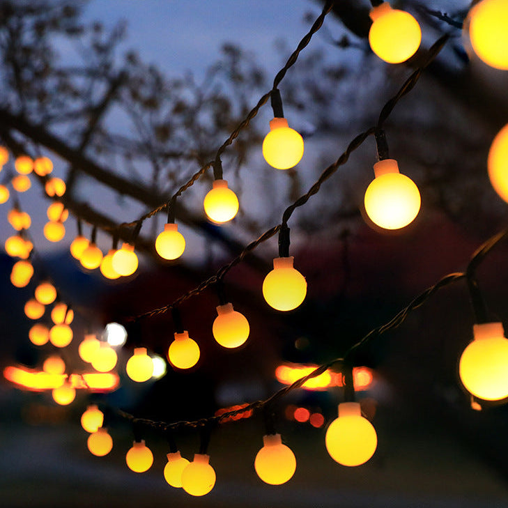 String of yellow lights hanging on tree branches against a dark background