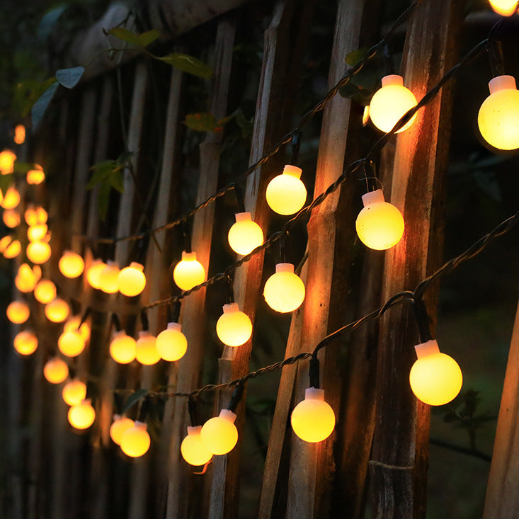 String of round lights hanging against a wooden fence