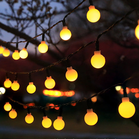 String of yellow lights hanging outdoors with a dark background
