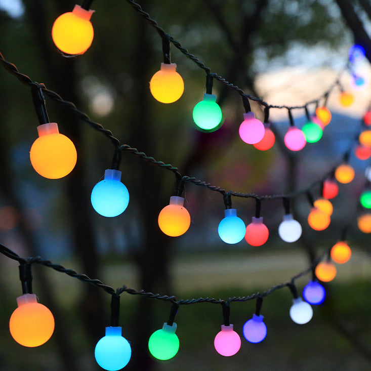 String of colorful LED lights hanging outdoors with a blurred background
